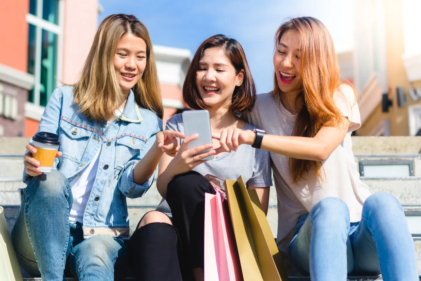 Friends checking a phone together while out shopping